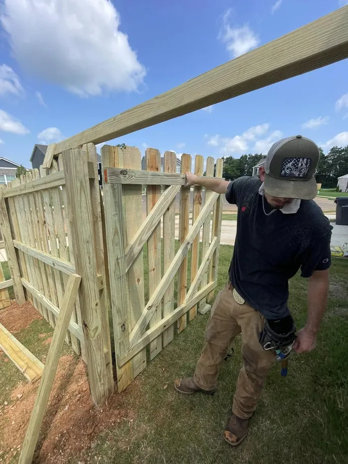 Crew member building a wooden drive gate frame on site in Alabama