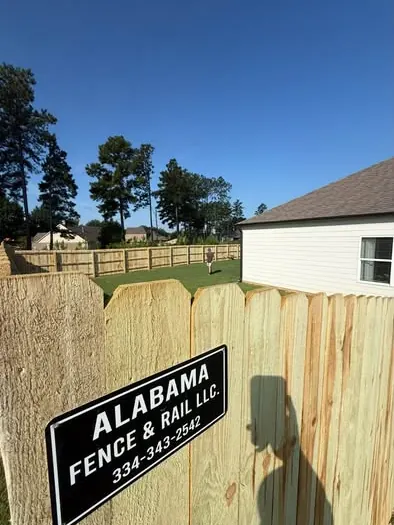 Alabama Fence and Rail yard sign mounted on a finished wood privacy fence