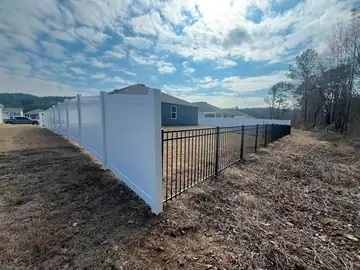 White vinyl privacy fence meeting a black aluminum section