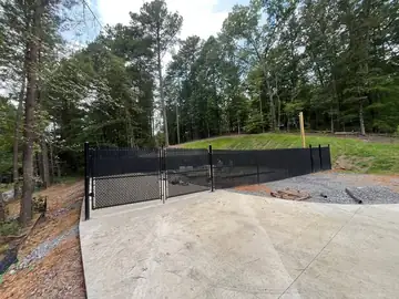 Black chain link fence and gate at a concrete pad