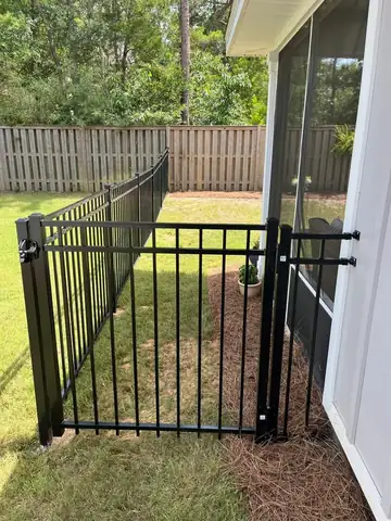 Black aluminum gate hung against the wall of a house