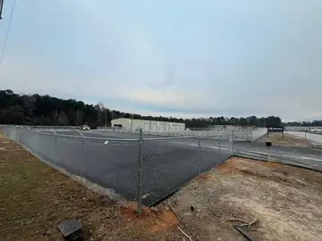 Galvanized chain link fence around a large concrete lot