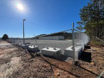 Chain link fence with barbed arms above concrete blocks