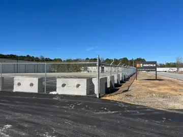 Long galvanized fence line beside a storage facility drive