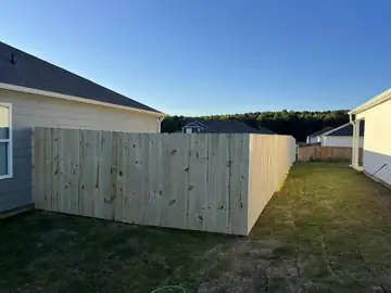 Wood privacy fence tied into the corner of a new-build house