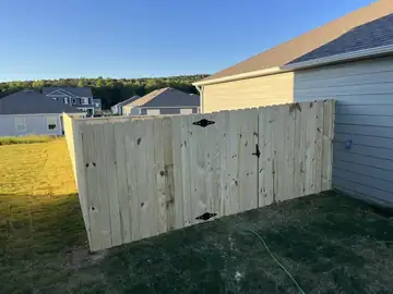Tall wood privacy fence panel against a house wall