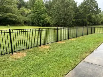 Black aluminum fence along a lawn and walkway