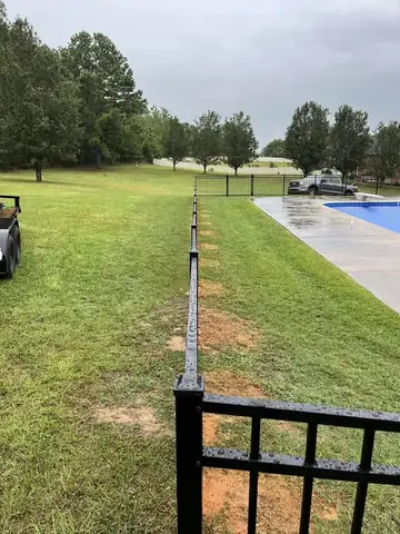 Black aluminum pool fence in wet weather