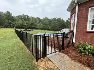 Black aluminum fence and gate at a brick house