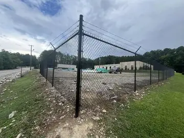 Corner of a black chain link fence at a commercial site