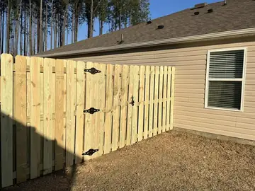 Wood privacy fence and gate at a house on a wooded lot
