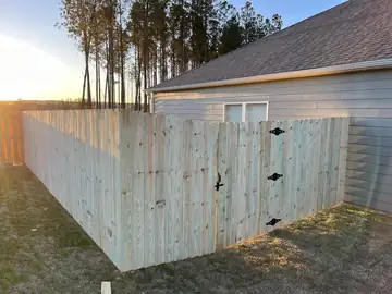 Wood privacy fence and gate along a garage wall