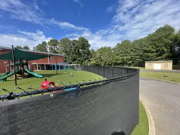 Black chain link fence with privacy screen at a school playground