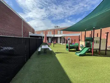 Play area with artificial turf enclosed by screened black fencing