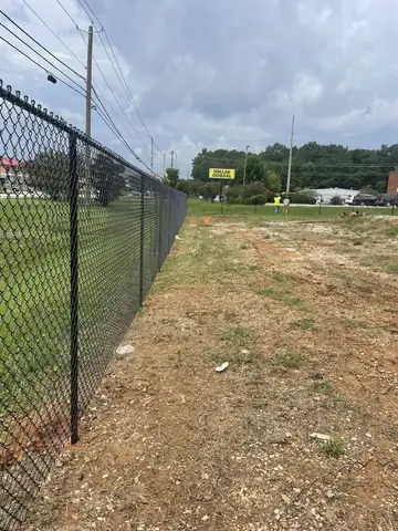 Black chain link fence line across open ground