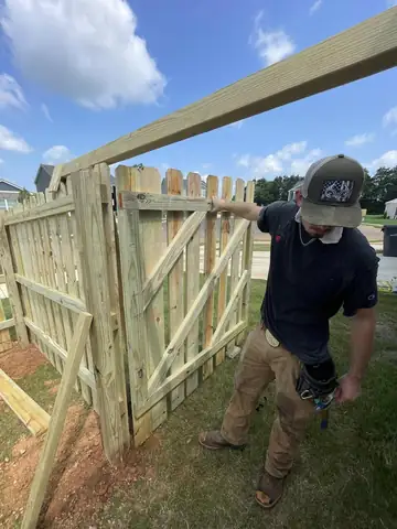 Crew member building a wooden drive gate on site