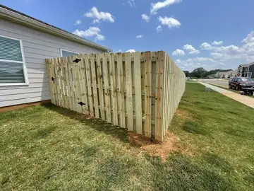 Wood privacy fence and gate beside a house