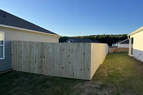 Wood privacy fence tied into the corner of a new-build house