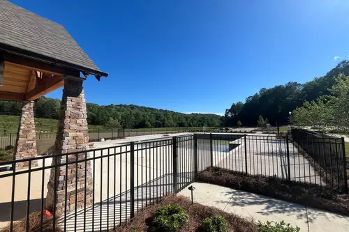 Black aluminum fence beside a stone pool pavilion