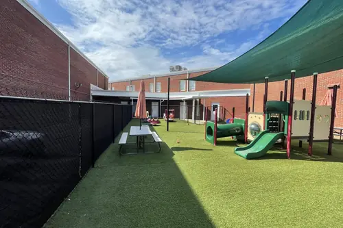 Play area with artificial turf enclosed by screened black fencing