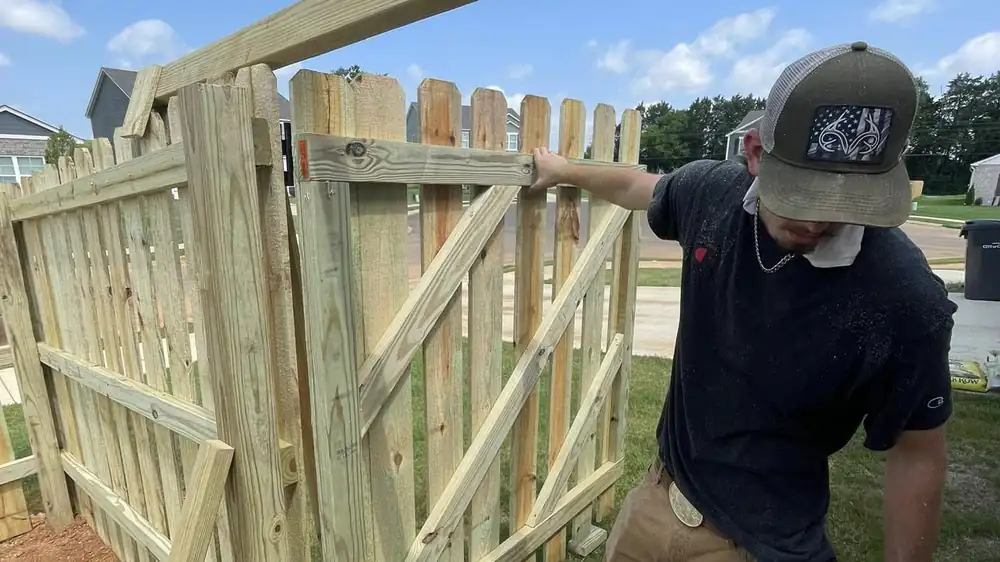 Crew member building a wooden drive gate frame on site