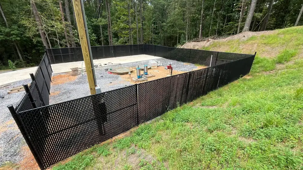 Black safety fencing installed on a graded construction slope for erosion control