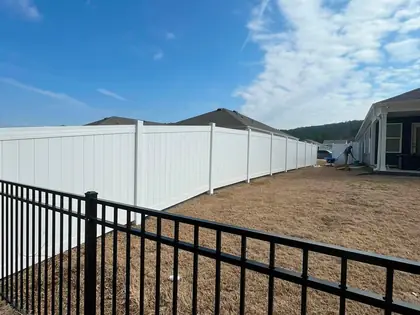 White vinyl privacy fence panels installed along a residential lot line