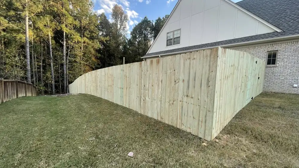 Wood privacy fence following the grade behind a new Alabama home